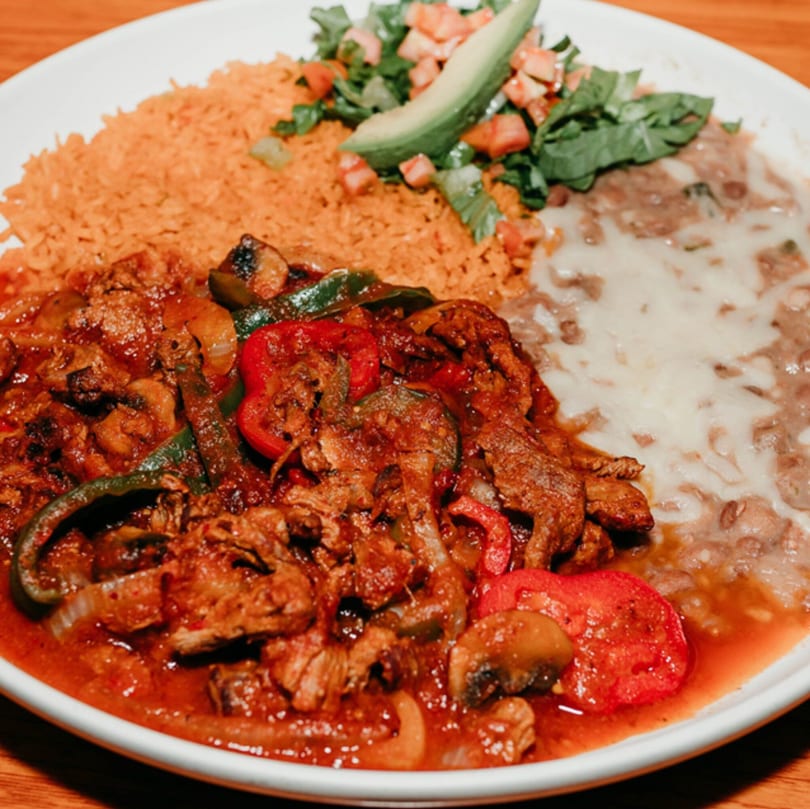 My Taco House's Mexican dish with meat, rice, beans, and a side salad with avocado.