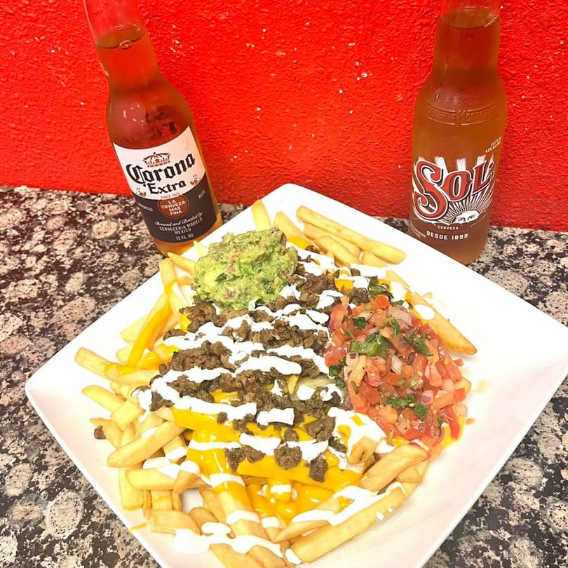 My Taco House carne asada fries with guacamole, pico de gallo, and two Mexican beer bottles.