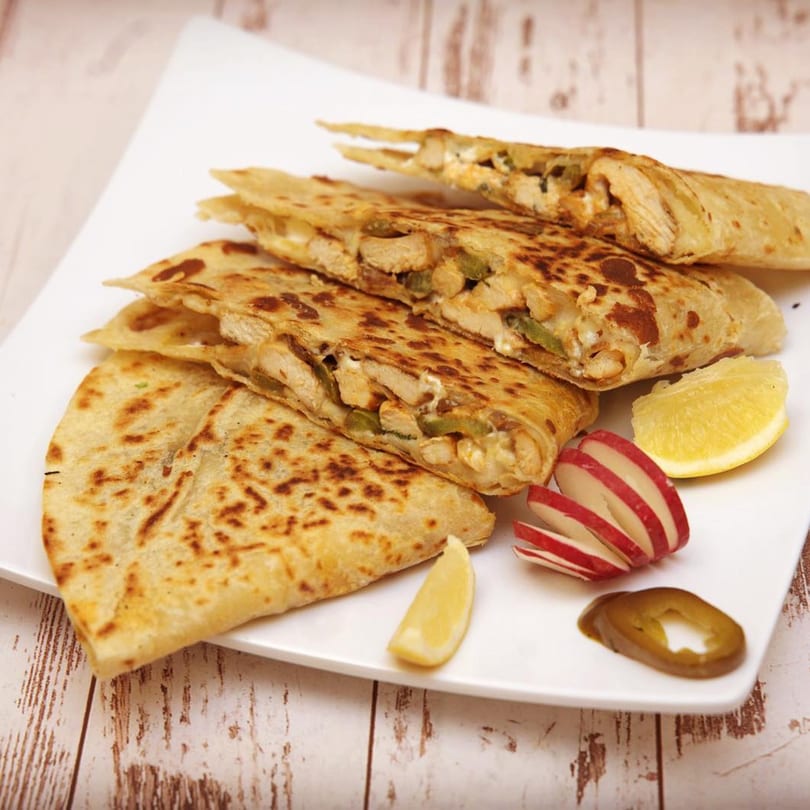 Chicken quesadillas with cheese and green peppers, served with lemon, radish, and jalapeño.