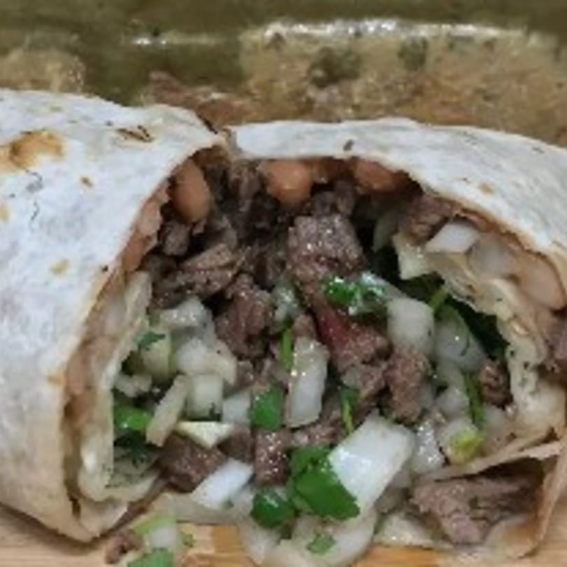 A large My Taco House burrito, cut in half, revealing steak, beans, onions, and cilantro.