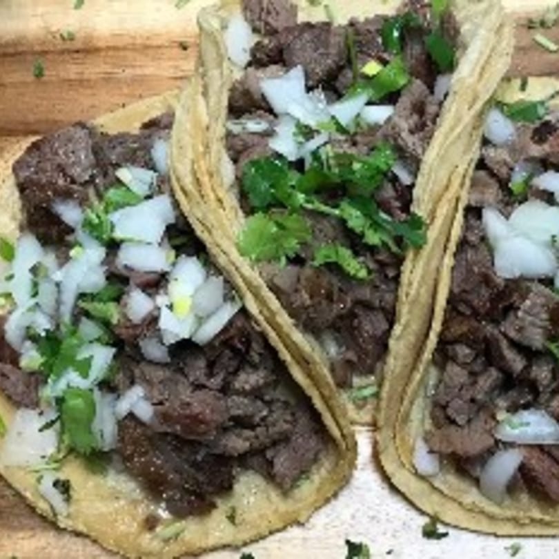 Three My Taco House Mexican street tacos with diced meat, onions, and cilantro.